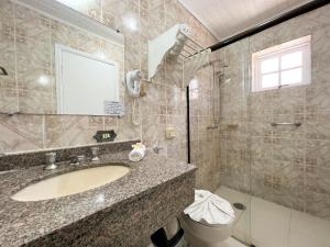a bathroom with a sink and a mirror and a toilet at Hotel Solar da Montanha in Campos do Jordão