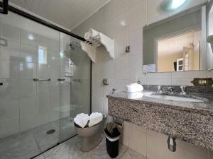 a bathroom with a shower and a sink and a toilet at Hotel Solar da Montanha in Campos do Jordão