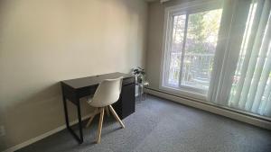 a desk with a white chair next to a window at Private Room in Oliver 104 ave, Across Grand McEwan University, Norquest College, A Chic Location! in Edmonton