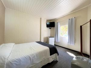 a bedroom with a white bed and a window at Hotel Solar da Montanha in Campos do Jordão
