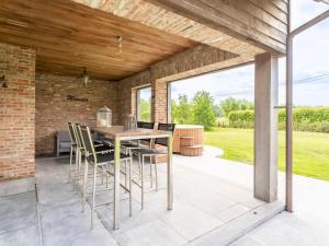 un patio con techo de madera, mesa y sillas en Landgoed Meersen en Maldegem
