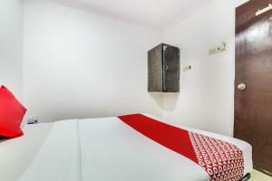 a white bedroom with a red and white bed at OYO 66982 Hotel Skyway Inn in Mumbai