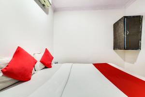 a white bed with red pillows in a room at OYO 66982 Hotel Skyway Inn in Mumbai