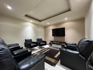 a living room with leather furniture and a flat screen tv at Hotel Solar da Montanha in Campos do Jordão