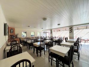 a dining room with tables and chairs and windows at Hotel Solar da Montanha in Campos do Jordão