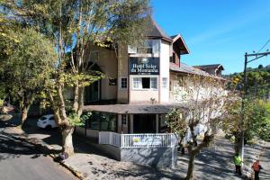 a building with a sign for a hotel with trees at Hotel Solar da Montanha in Campos do Jordão