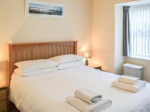 a bedroom with a white bed with towels on it at Driftwood in Sutton on Sea