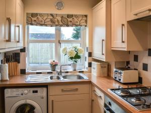 a kitchen with a sink and a washing machine at Driftwood in Sutton on Sea