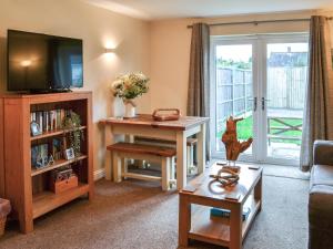 a living room with a tv and a table and a couch at Driftwood in Sutton on Sea