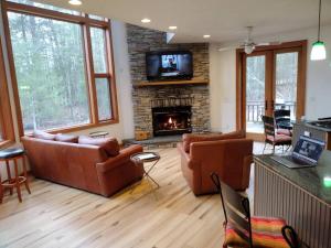 sala de estar con muebles de cuero y chimenea en Lake Front Heated Floors Hot Tub Firepit Secluded, en Eldred