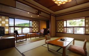ein Wohnzimmer mit einem Tisch, Stühlen und Fenstern in der Unterkunft Zao Onsen Omiya Ryokan in Zao Onsen