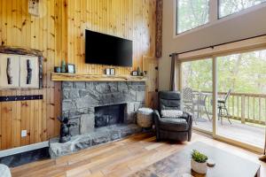 un salon avec une cheminée en pierre et une télévision dans l'établissement The Bee Branch 23, à Sugar Mountain