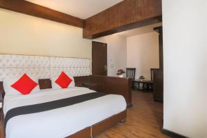 a bedroom with a large white bed with red pillows at OYO Flagship 69755 Hotel Parktel in Ghaziabad