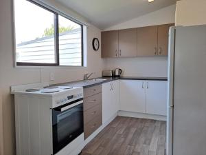 a kitchen with white cabinets and a stove and a window at Surfers Dream - 2min from beach in Dunedin