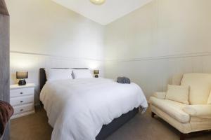 a white bedroom with a bed and a couch at HiderWay - Perched overlooking Warrnambool's landmarks in Warrnambool
