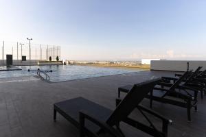 a swimming pool with a group of chairs around it at Amber Cove Impression City Melaka By Dawn Stay Free Netflix in Melaka