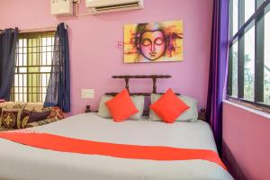 - une chambre avec des murs roses et un lit avec des oreillers orange dans l'établissement OYO Aradhya Regency, à Konârak