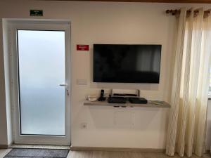 a flat screen television on a wall next to a door at Paradise Apartments III in Santa Cruz das Flores