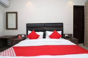 Bett mit roten Kissen und einer roten Decke in der Unterkunft OYO Flagship Hotel Madhurapuri in Kozhikode