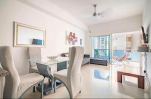 ein Wohnzimmer mit einem Glastisch und Stühlen in der Unterkunft Apartamento lujoso a un minuto de la playa del laguito, la mejor playa de Cartagena de Indias in Cartagena de Indias