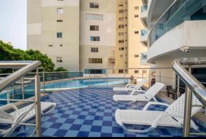 einen Balkon mit Stühlen und einen Pool auf einem Gebäude in der Unterkunft Apartamento lujoso a un minuto de la playa del laguito, la mejor playa de Cartagena de Indias in Cartagena de Indias