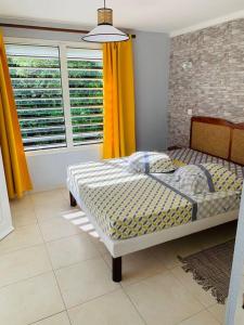 a bedroom with a bed and a window with yellow curtains at Villa Salako, Terre-de-Bas - Bas de Villa in Terre-de-Bas