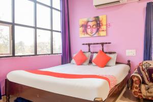 - une chambre avec des murs roses et un lit avec des oreillers orange dans l'établissement OYO Aradhya Regency, à Konârak