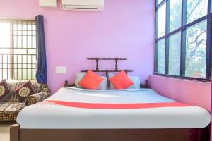 - une chambre avec un lit aux murs roses et des fenêtres dans l'établissement OYO Aradhya Regency, à Konârak