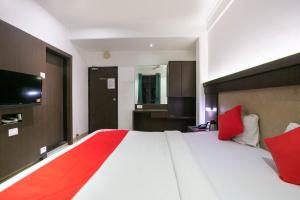 a bedroom with a large white bed with red pillows at Hotel Prince Residency in Thane