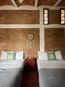 a room with two beds and a brick wall at Hosteria Chata Adults Only in Lo de Marcos