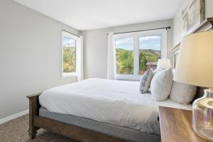 a white bedroom with a bed and two windows at Mountain View Wintergreen Home 84140 in Blue Mountains