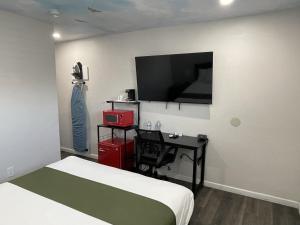 Schlafzimmer mit einem Bett, einem Schreibtisch und einem TV in der Unterkunft Fontana Inn in Fontana