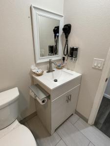 La salle de bains est pourvue d'un lavabo, d'un miroir et de toilettes. dans l'établissement Fontana Inn, à Fontana