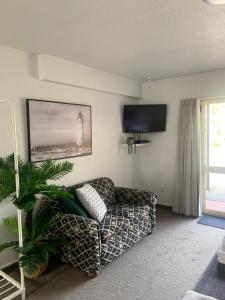 uma sala de estar com um sofá e uma televisão de ecrã plano em Apex Motorlodge em Nelson