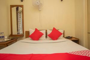 a bedroom with a bed with red pillows at Capital O Hotel Red Cherry in Gangtok