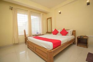 a bedroom with a large bed with red pillows at Capital O Hotel Red Cherry in Gangtok