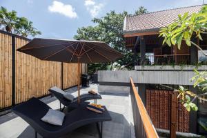 a patio with two chairs and an umbrella at Villa Tamara Canggu Bali in Kerobokan