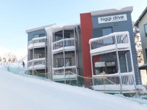 un edificio de apartamentos en la nieve con un cartel en 2 Higgi Drive - Ski in Ski Out, en Monte Hotham