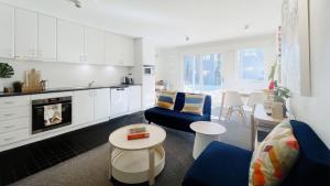 a kitchen and living room with white cabinets and blue chairs at Apartment 10 The Stables Perisher in Perisher Valley