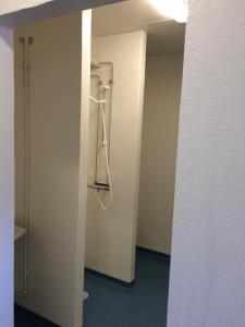 a bathroom with a shower in a white wall at Eskilstuna Hostel in Eskilstuna