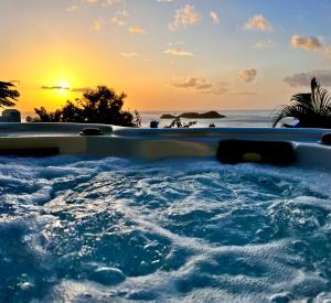 a hot tub with the sunset in the background at Sunset Lodge in Bouillante