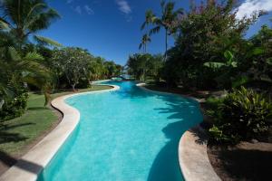 una piscina en un complejo con agua azul y palmeras en Vaiava Beach Carlton- Tahiti - beachfront luxury residence & pool - 4 pers, en Punaauia