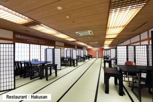 a dining room with tables and chairs and windows at Manten no Tsujinoya in Komatsu