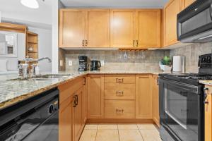 a kitchen with wooden cabinets and a sink and a stove at ⭐️ Luxury Mountain View Studio in Canmore ⭐️ in Canmore
