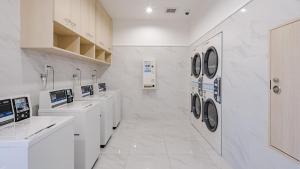 lavadero blanco con lavabos y lavadoras en Toyoko Inn Imba Nihon-idai Ekimae, en Inzai