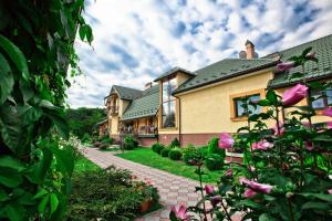 une maison avec un jardin agrémenté de fleurs roses dans la cour dans l'établissement Pansionat Bogema, à Trouskavets