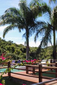 a wooden bench with palm trees and flowers at MarTito Forno Pousada - Armação dos Buzios in Búzios