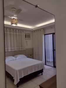 um quarto com uma cama branca e uma ventoinha de tecto em Leotel hospedagem em Serra