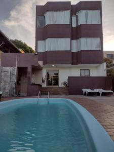 a house with a swimming pool in front of a building at Leotel hospedagem in Serra