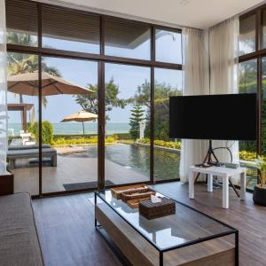 a living room with a tv and a large window at Tolani Le Bayburi Villas, Hua Hin - Pranburi in Pran Buri